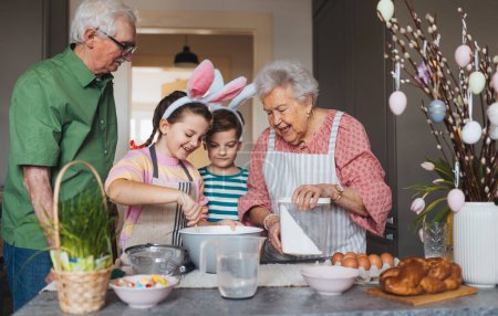 Großeltern mit Enkeln bereiten traditionelle Osterspeisen zu, backen Kuchen und Süßigkeiten. Die Weitergabe von Familienrezepten, Brauchtum und Geschichten. Konzept für Familien-Osterferien.