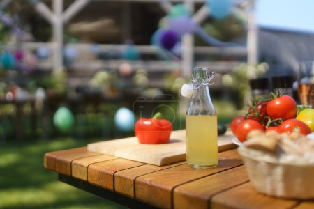 Téléchargez les photos : Gros plan d'un gril et d'une table lors d'une garden party estivale. Table d'appoint avec verres à vin, limonade, légumes frais et pain. - en image libre de droit