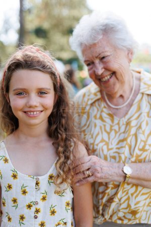 Photo for Portrait of young girl with grandmother at garden party. Love and closeness between grandparent and grandchild. - Royalty Free Image