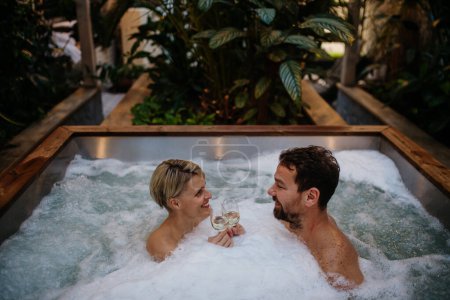 Foto de Hermosa pareja madura relajarse en la bañera de hidromasaje, beber champán, disfrutar de un romántico fin de semana de bienestar en el spa. Concepto de Día de San Valentín. - Imagen libre de derechos