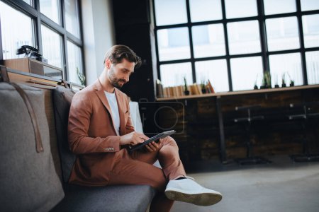 Photo for Handsome businessman preparing for meeting, working on presentation on tablet, sitting in modern office. Working remotely from coffee shop. - Royalty Free Image