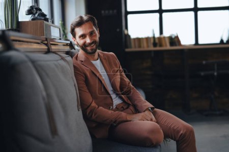 Photo for Portrait of handsome businessman in suit sitting in modern office, smiling, looking at camera. Working remotely from coffee shop. - Royalty Free Image