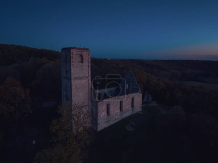 Téléchargez les photos : Vue aérienne de vieilles ruines du château historique au milieu de la forêt. Vue par drone du paysage naturel avec forteresse brisée pendant le coucher du soleil. - en image libre de droit