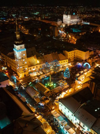 Photo for Aerial night shot of city during Christmas, winter and christmas decorations on city square. Chistmas market during holiday season in small city. - Royalty Free Image