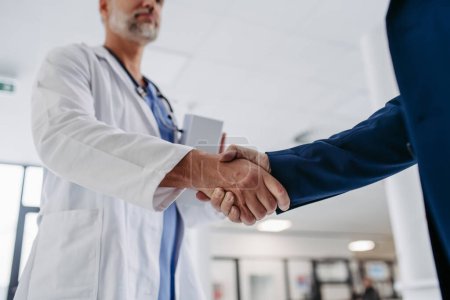 Photo for Close up of pharmaceutical sales representative standing in doctor office, shaking hands. Hospital director, manager of private medical clinic greeting new doctor. Generous donor, giving donation to - Royalty Free Image
