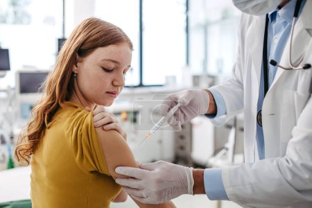 Photo for Doctor, pediatrician injecting vaccine into teenage girl arm. Concept of preventive health care and vaccination for teenagers, immunisation. - Royalty Free Image