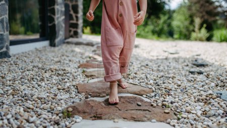 Photo for Close up of little girl walking barefoot near a forest cotage, weekend activities during summer day. - Royalty Free Image