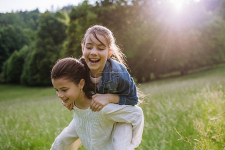 Dos hermanas jugando en el prado en la hierba alta, divirtiéndose, apoyándose mutuamente. Hermandad amor y hermanos concepto de relación.