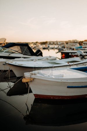 Téléchargez les photos : Un petit bateau sur l'eau calme, amarré dans le port, quai pendant le coucher du soleil. - en image libre de droit