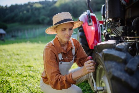 Foto de Agricultora fijando una rueda en un tractor. Campesina progresista trabajando en tractores en su propia granja. Mujeres en la agricultura. - Imagen libre de derechos