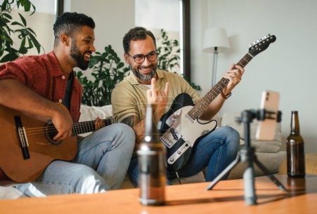 Beste Freunde, Musiker jammen zusammen, drehen Videos in den sozialen Medien. Gemeinsam Musik auf akustischer und elektrischer Gitarre zu Hause für Fans zu spielen. Konzept der Männerfreundschaft, Bromance.