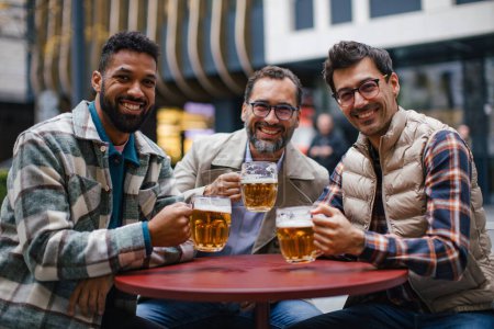 Téléchargez les photos : Meilleurs amis togehter, boire de la bière dans le bar de la ville et parler, s'amuser et rire. Concept d'amitié masculine, bromance. - en image libre de droit
