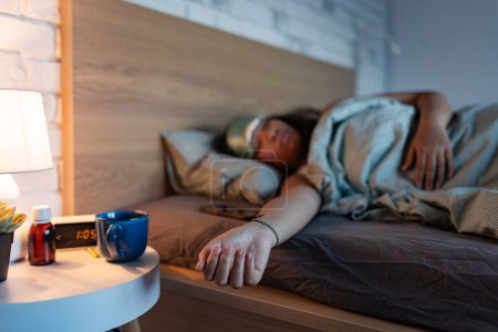 Woman sleeping with sleep mask, using sleeping pills, melatonin supplements. Concept of sleep routine. Insomnia a sleep problems among adults.
