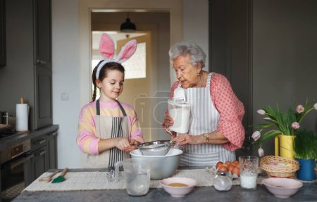 Photo for Grandmother with grandaughter preparing traditional easter meals, baking cakes and sweets. Passing down family recipes, custom and stories. Concept of family easter holidays. - Royalty Free Image