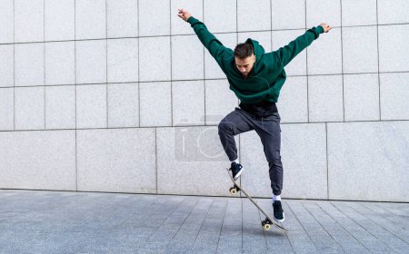 Foto de Un joven patinando en la ciudad. Elegante entrenamiento de skate en skate park. Concepto de skate como deporte y estilo de vida. - Imagen libre de derechos