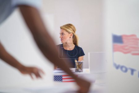 Foto de Mujer miembro de la comisión electoral en el lugar de votación el día de las elecciones, EE.UU. elecciones. - Imagen libre de derechos