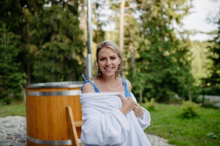 Téléchargez les photos : A young woman preapring to get into hot bath outdoors. Summer holidays in the mountains, hot water treatments and thermal spa concept. - en image libre de droit