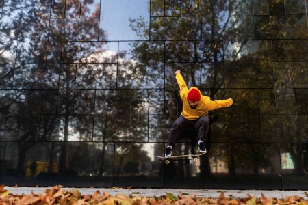 Téléchargez les photos : Skateboarder homme patiner en ville, sauter, ollie jump. Entraînement élégant de skateboarder dans le skate park. Concept de skateboard comme sport et style de vie. - en image libre de droit