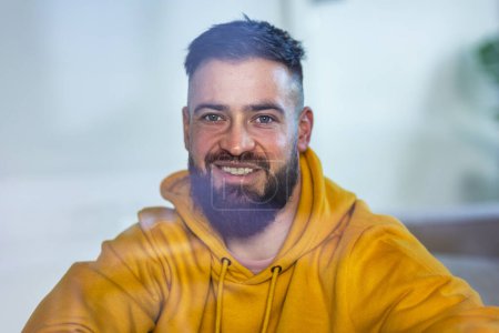 Photo for Calm man in yellow sweatshirt looking at camera and smiling. - Royalty Free Image