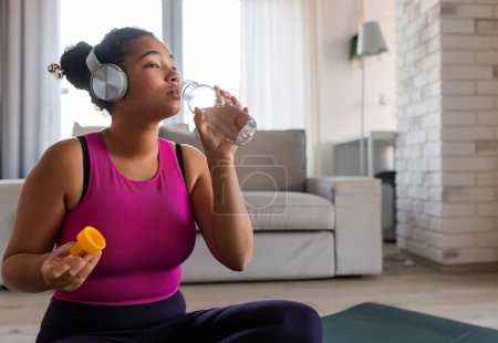 Photo for Woman resting after home workout, drinking water from bottle. New Years resolutions, healthy lifestyle, losing weight and selfcare. Concept of morning or evening workout routine. - Royalty Free Image