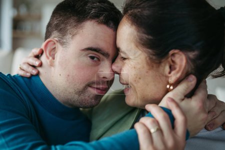 Portrait d'un jeune homme trisomique avec sa mère à la maison, grillé au jus. routine du matin pour les hommes atteints de syndrome de Down trouble génétique.