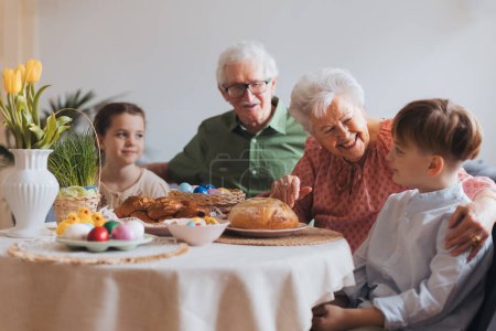 Großeltern mit Enkeln beim traditionellen Osteressen. Die Wiederherstellung familiärer Traditionen und Bräuche. Konzept für Familien-Osterferien.