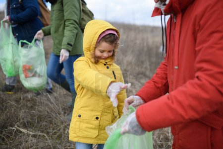 Téléchargez les photos : Jeune fille parmi les éco-activistes ramasser des déchets dans la nature, la pollution de l'environnement, l'éco-activisme et le concept de labourage. - en image libre de droit