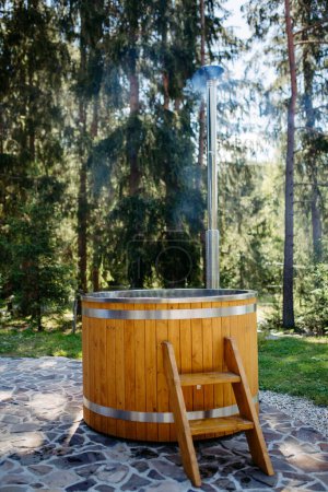 Téléchargez les photos : A wooden bathtub with a fireplace to burn wood and heat water in backyard in mountains. - en image libre de droit