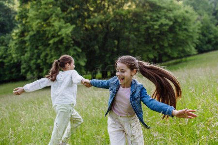 Zwei Schwestern spielen auf einer Wiese im hohen Gras, haben Spaß und lachen. Schwesternliebe und Geschwisterbeziehungskonzept.