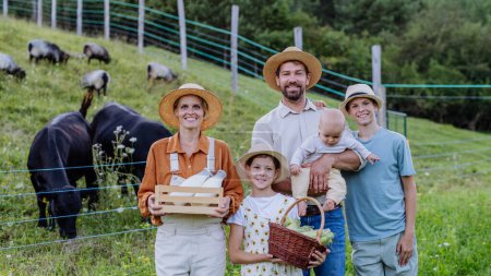 Téléchargez les photos : Portrait de la famille d'agriculteurs exploitant panier de récolte plein de légumes frais, debout devant le paddock. Concept d'agriculture multigénérationnelle et familiale. - en image libre de droit