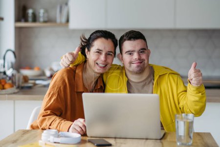 Photo for Mom teaching a young man with down syndrome, using laptop. Telehealth consultation with doctor. - Royalty Free Image
