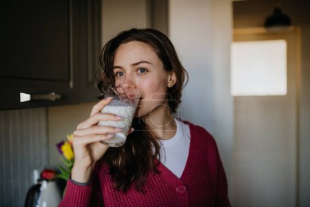 Schöne Frau trinkt ein Glas pflanzliche Milch in der Küche.
