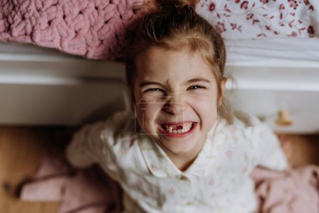 Foto de Retrato de una linda chica sonriendo con una sonrisa de dientes huecos, perdiendo sus dientes de bebé delanteros superiores. - Imagen libre de derechos