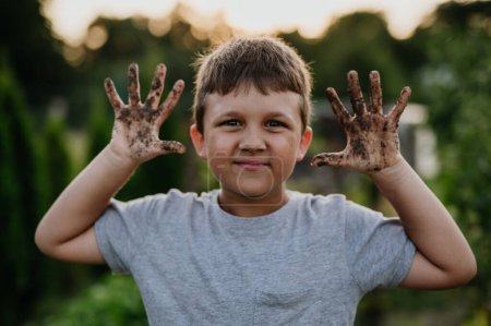 Foto de El muchacho tiene las manos sucias después del trabajo en el jardín, mostrando la tierra en las palmas. Cuidar un huerto y cultivar, plantar verduras de primavera. - Imagen libre de derechos
