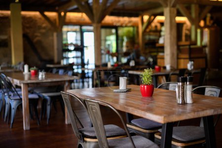 Photo for Modern restaurant with wooden tables, chairs, and flooring. Ambient atmosphere, rustic interior design. Earthy modern, nauralistic design. - Royalty Free Image