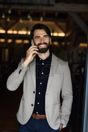 Téléchargez les photos : Portrait d'homme d'affaires mature en costume veste debout à l'intérieur dans le bureau moderne, faire un appel téléphonique. - en image libre de droit