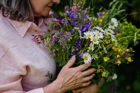 Foto de La mujer sostiene un hermoso ramo de flores del prado. Una colorida variedad de flores silvestres de verano. - Imagen libre de derechos