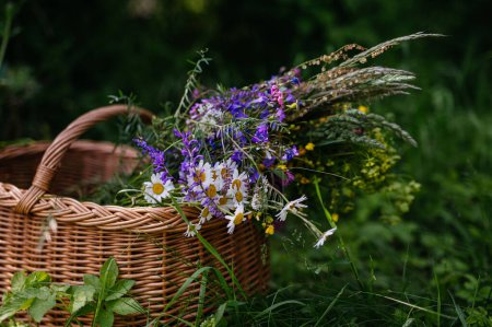 Foto de Cesta de mimbre llena de flores de prado. Una colorida variedad de flores silvestres de verano. - Imagen libre de derechos