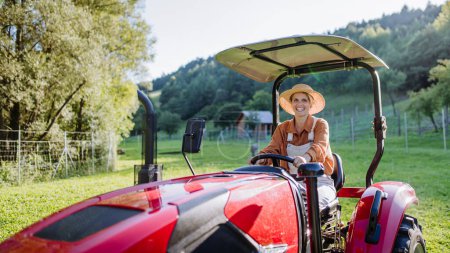 Téléchargez les photos : Une agricultrice progressiste conduisant un tracteur sur sa propre ferme. Concept de la femme dans l'agriculture. - en image libre de droit