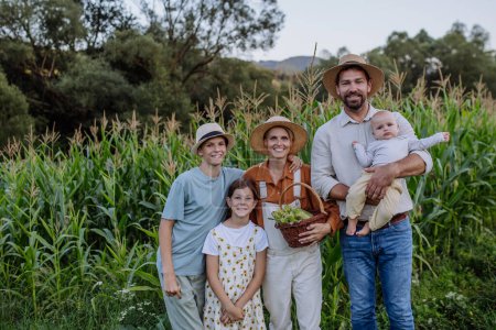 Bauernfamilie steht mit Mais vor einem Feld. Konzept der Mehrgenerationen- und Familienlandwirtschaft.