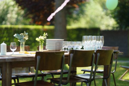 Plan rapproché de la table dressée à la garden party d'été, assiettes vides et verres. Cadre de table avec verres, limonade, délicate décoration florale et papier.