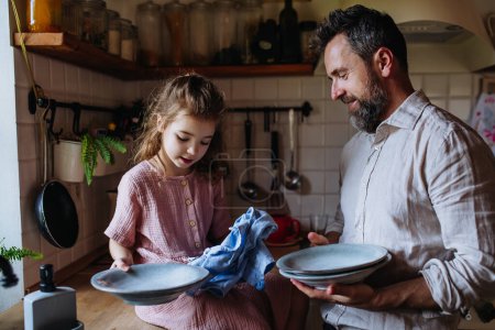 Dad and daughter cooking together in kitchen, cleaning fruit in sink. Girls dad. Unconditional paternal love and Fathers Day concept.
