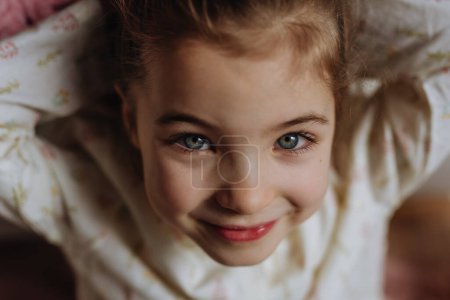 Portrait de la petite fille vue de dessus, charmante jeune femme avec de beaux yeux regardant la caméra et souriant.