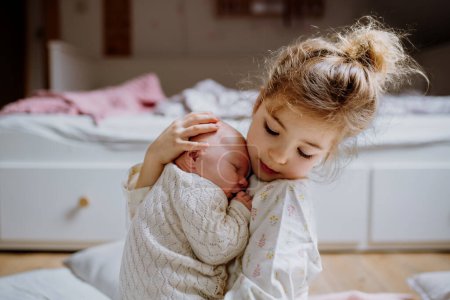 Photo for Portrait of big sister holding newborn sister. Girl carefully cuddling little baby. Sisterly love, joy for new family member. - Royalty Free Image