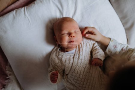 Draufsicht auf niedliches kleines Baby, das im Bett schläft, große Schwester streichelt neugeborene Wange. Schwesternliebe, neues Familienmitglied.