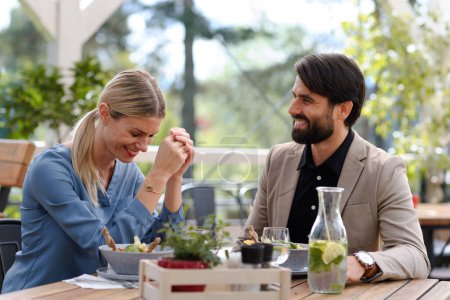 Téléchargez les photos : Couple assis à l'extérieur sur la terrasse restaurant, ayant rendez-vous dîner romantique. Déjeuner d'affaires pour deux gestionnaires, discussion sur un nouveau projet d'entreprise. - en image libre de droit