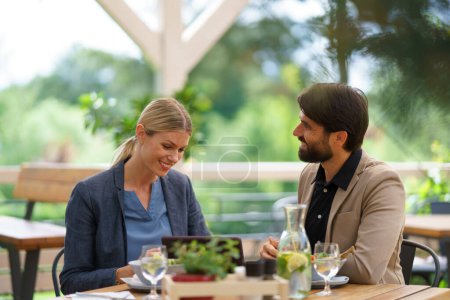 Téléchargez les photos : Déjeuner d'affaires pour deux gestionnaires, discussion sur un nouveau projet d'entreprise. Couple assis à l'extérieur sur la terrasse restaurant, ayant rendez-vous pour dîner romantique. - en image libre de droit