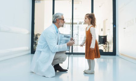 Kleines Mädchen im Gespräch mit einem Arzt in der Krankenhauslobby. Freundschaftliche Beziehung zwischen medizinischem Personal und dem Kinderpatienten.