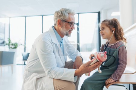 Kleines Mädchen lauscht dem Herzschlag der Plüschtiere mit Stethoskop. Rollentausch. Freundschaftliche Beziehung zwischen Arzt und Patient. Emotionale Unterstützung für Kinder.