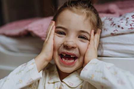 Foto de Retrato de una linda chica sonriendo con una sonrisa de dientes huecos, perdiendo sus dientes de bebé delanteros superiores. - Imagen libre de derechos
